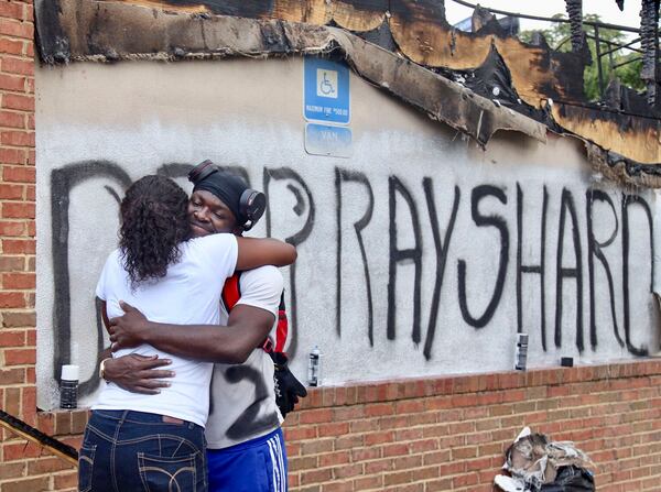 Eva Snow and Joseth Jett hug after Jett spray-painted over the top of graffiti from the night before and painted RIP Rayshard. People began showing up at Wendy's on University Avenue Sunday morning, June 14, 2020.  Some helped with cleanup, some came to look, and some began placing flowers and created a memorial.  On Saturday, protesters set fire to the Atlanta Wendy's where Rayshard Brooks, a 27-year-old black man,  was shot and killed by Atlanta police Friday evening during a struggle at a Wendy's drive-thru line. (Photo: Steve Schaefer for The Atlanta Journal-Constitution)