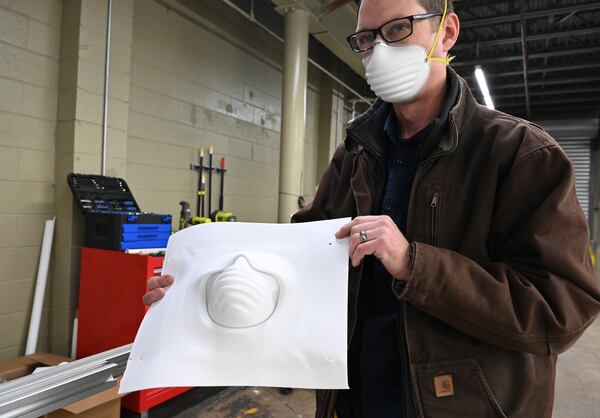 Engineer Whit Costley holds a sheet being formed into the shape of new N95 mask. He used a temporary prototype molding station at ThermoPore Materials Corporation, a plastics manufacturer in Newnan that received government approval to make a new type of N95 that utilizes a different filtration material. (Hyosub Shin / Hyosub.Shin@ajc.com)