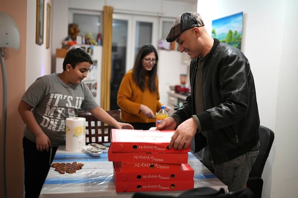 Hasan Zaheda, right, Nour Essa, center and their son Riad prepare pizza for the iftar – during the Ramadan the meal breaking the day's fast – in their house in Rome, Sunday, March 2, 2025. (AP Photo/Alessandra Tarantino)