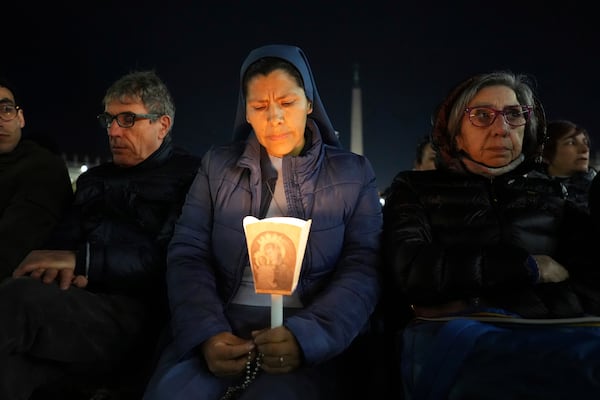 A woman holds a candle as Cardinal Robert Francis Prevost, Prefect of the Dicastery for Bishops, leads the recitation of the Holy Rosary for Pope Francis' health in St Peter's Square at the Vatican, Monday, March 3, 2025. (AP Photo/Kirsty Wigglesworth)