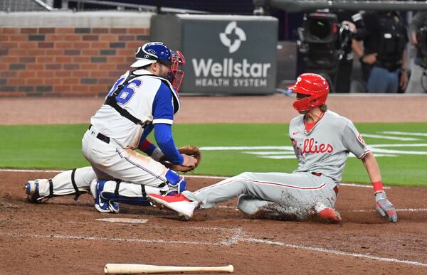 Philadelphia Phillies third baseman Alec Bohm (28) slide toward home as Braves catcher Travis d'Arnaud (16) secures the ball before applying a tag in the ninth inning Sunday, April 11, 2021, at Truist Park in Atlanta. Bohm was ruled safe, though Atlanta argued he never touched home plate. Philadelphia won 7-6. (Hyosub Shin / Hyosub.Shin@ajc.com)