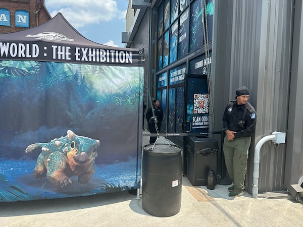 "Jurassic World: The Exhibit" has beefed up security after vandals damaged the experience on May 28, 2023. Here is a guard outside on reopening day June 7, 2023. RODNEY HO/rho@ajc.com