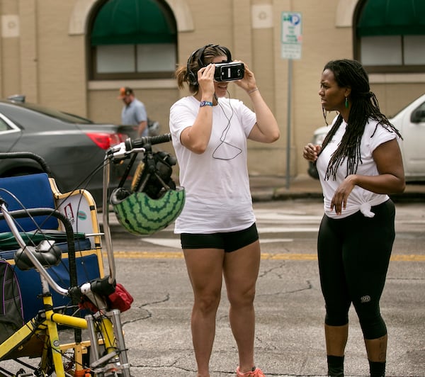 SXSW Interactive began Friday, March 11, 2016 and the crowd began to gather around various locations in downtown Austin. Pedicab cyclist, Danielle Day tries out the VRonDemand by Samsung while fellow pedicab cyclist Erica Gafken checks it out from the outside.  LAURA SKELDING/AMERICAN-STATESMAN