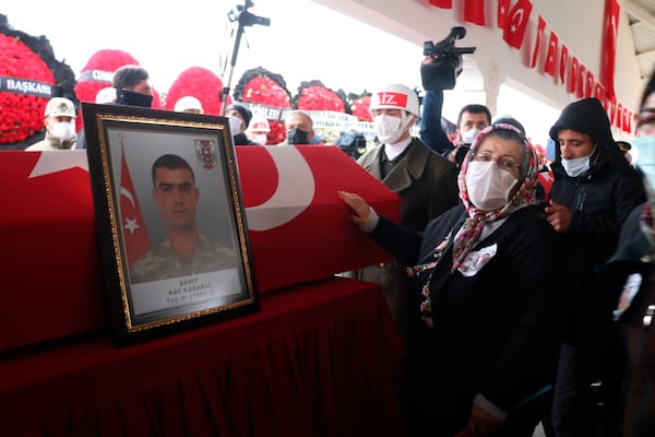 FILE - The grandmother of Turkish soldier Adil Kabakli, one of thirteen Turkish soldiers, police and civilians who had been abducted by Kurdish insurgents and found killed in northern Iraq, touches his national flag-draped coffin during the funeral for both Kabakli and fellow soldier Muslum Altintas in Gaziantep, southeastern Turkey, Tuesday, Feb. 16, 2021. (IHA via AP, File)