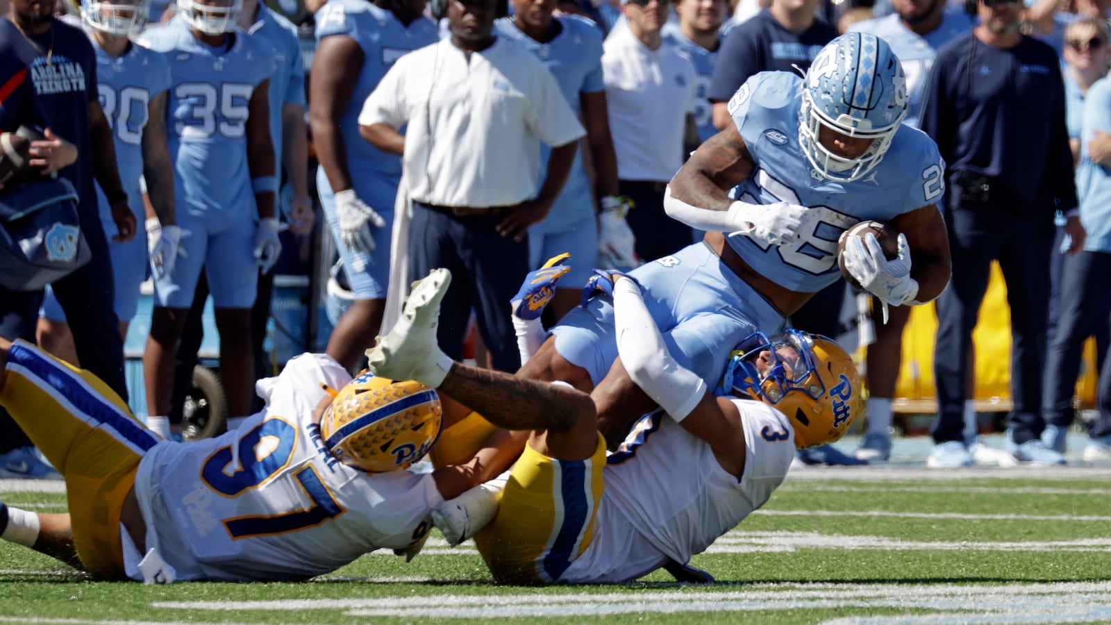 North Carolina running back Omarion Hampton (28) is tackled by Pittsburgh defensive lineman Isaiah Neal (97) and defensive back Donovan McMillon (3) during the first half of an NCAA college football game Saturday, Oct. 5, 2024, in Chapel Hill, N.C. (AP Photo/Chris Seward)