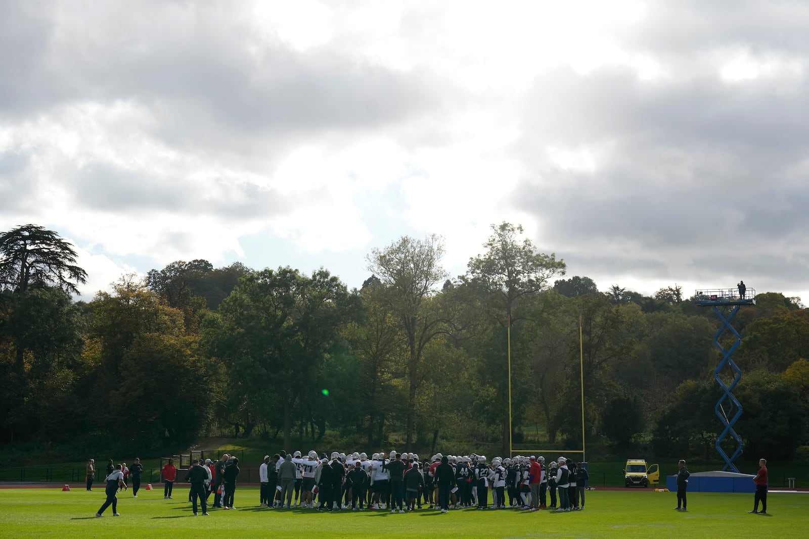 New England Patriots players huddle up during NFL football practice, Friday, Oct. 18, 2024, in Harrow, England. (AP Photo/Steve Luciano)