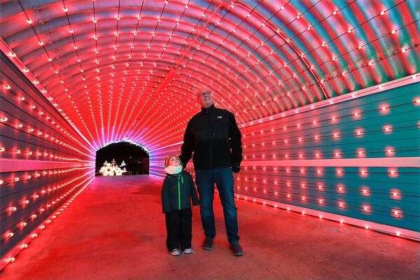 Ralph Thomas and his grandson Logan Thomas make their way through a new tunnel of lights in Margaritaville at Lanier Islands in this file photo from Nov. 2018. Curtis Compton/ccompton@ajc.com