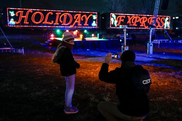 Eden Jordan, left, poses for her father Tim Jordan, right, in front of the CSX Holiday Express, Thursday, Nov. 21, 2024, in Erwin, Tenn. The railway company held a celebration and concert for the town affected by Hurricane Helene. (AP Photo/George Walker IV)