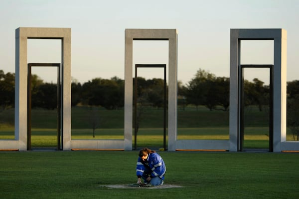 FILE - Texas A&M Emergency Care Team volunteer Linda Salzar, a recent masters graduate, kneels at the center pole marker at the Texas A&M Bonfire Memorial, Tuesday, Nov. 17, 2009, in College Station, Texas. (Tom Fox/The Dallas Morning News via AP, File)