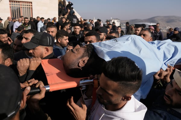 Mourners carry the bodies of two Palestinians Akram Abu Arrah, seen, and Mohammad Ghannam, both killed in an airstrike Israel said targeted a militant cell, during their funeral in the West Bank village of Al-Aqaba, Tuesday Dec. 3, 2024. (AP Photo/Majdi Muhammad)