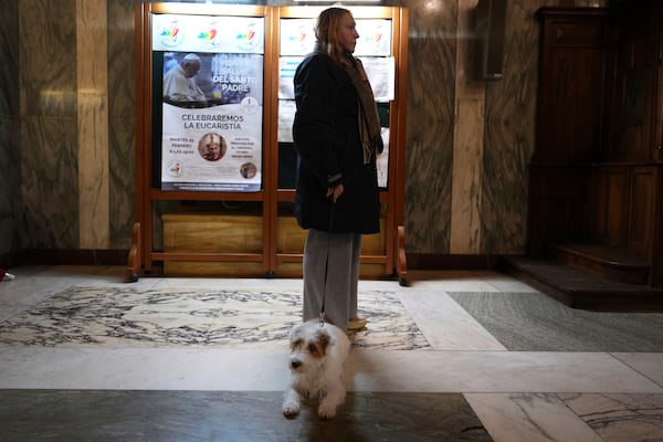 A woman and her dog listen as Pope's Vicar for Rome, Cardinal Baldassare Reina celebrates mass for the health of Pope Francis at the Church of the Argentinas, Santa Maria Addolorata in Rome, Italy Tuesday, Feb. 25, 2025. (AP Photo/Kirsty Wigglesworth)