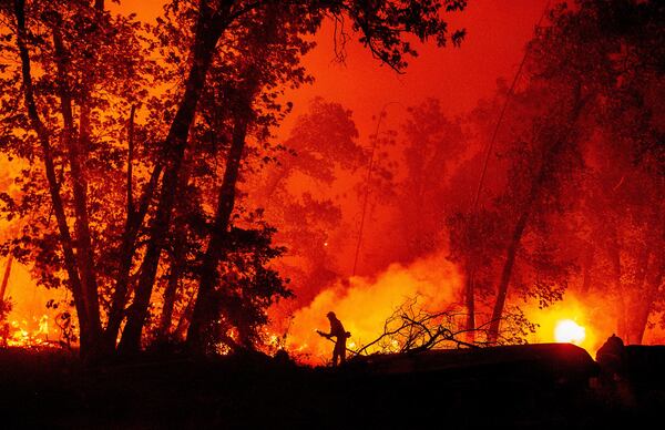 A firefighter douses flames as they push toward homes during the Creek fire in the Cascadel Woods area of unincorporated Madera County, California, on Sept. 7. A firework at a gender-reveal party triggered a wildfire in Southern California that has destroyed thousands of acres and forced many residents to flee their homes. 