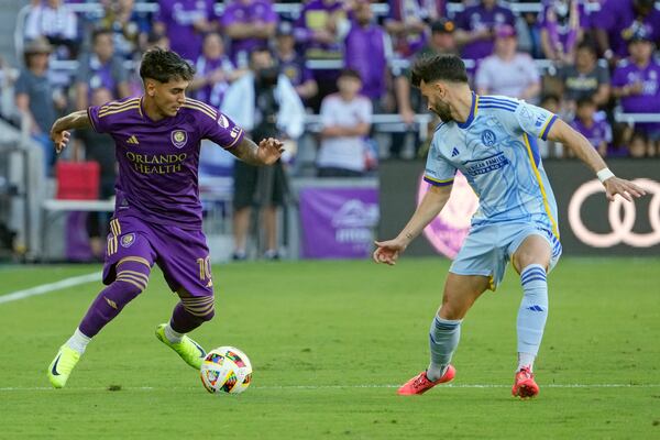 Orlando City's Facundo Torres, left, moves the ball against Atlanta United's Pedro Amador, right, during the first half of an MLS Semifinal Conference playoff soccer match, Sunday, Nov. 24, 2024, in Orlando, Fla. (AP Photo/John Raoux)