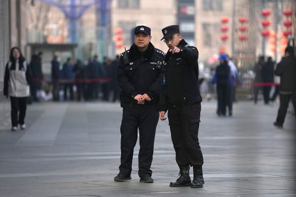 Chinese police officers monitor journalists gathered near a meeting of family members of passengers who were on board the MH370 Malaysia Airline jet that went missing in 2014 in Beijing, China, Saturday, March 8, 2025. (AP Photo/Ng Han Guan)