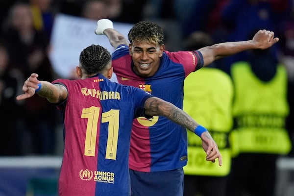 Barcelona's Raphinha, left, celebrates with his teammate Lamine Yamal after scoring his side's opening goal during the Champions League round of 16 second leg soccer match between FC Barcelona and SL Benfica at the Lluis Companys Olympic Stadium in Barcelona, Spain, Tuesday, March 11, 2025. (AP Photo/Emilio Morenatti)