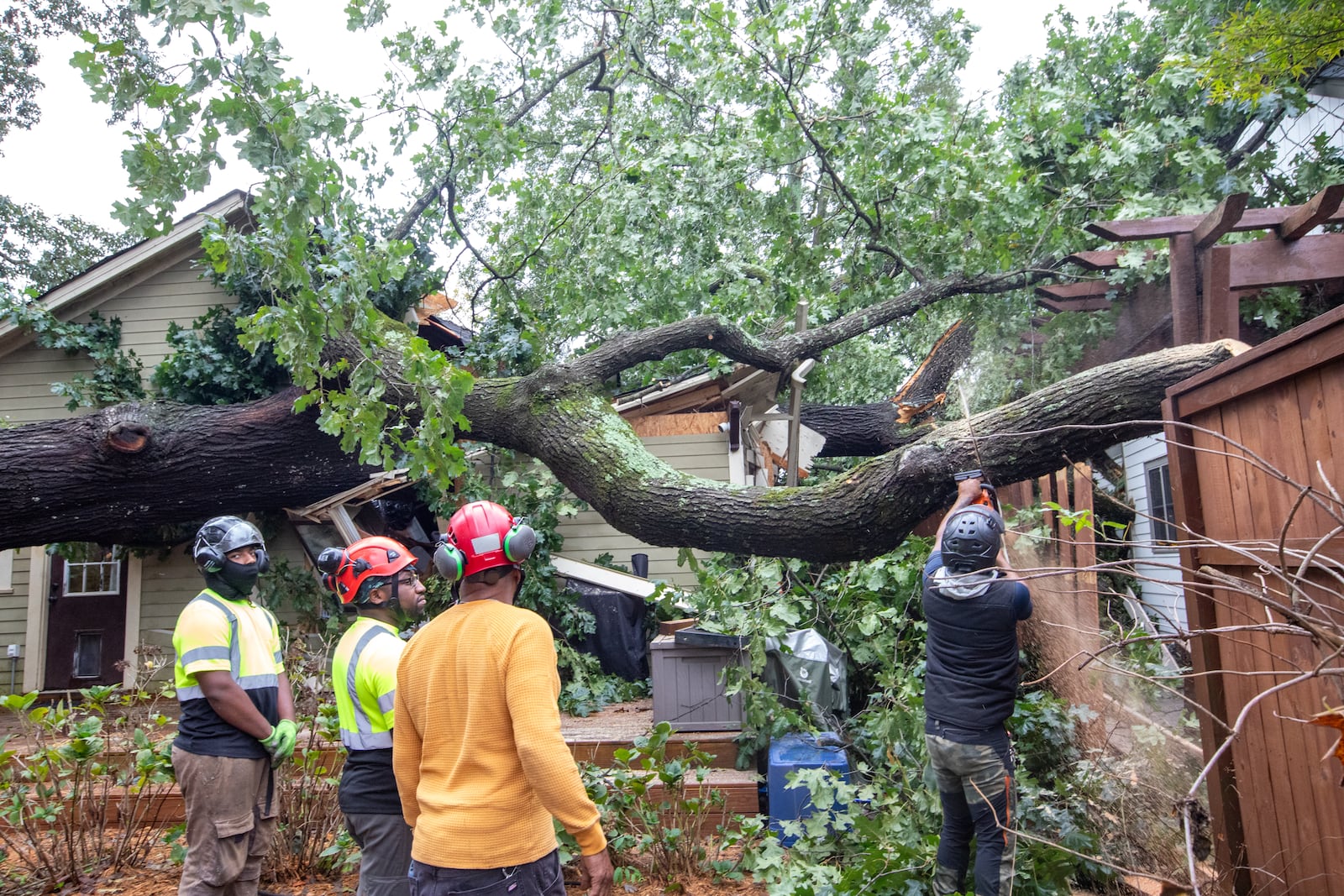 Dad’s Tree Service, including Markel Crear, from left, Mike Crear, Gary Cooper and Anthony Ray work to remove an oak tree from a Kirkwood home on Friday, Sept 27, 2024 after it fell on around 5:45 am during hurricane Helene.  Several homes were damaged in this area with multiple large oak trees falling in backyards. No one was hurt and residents are waiting for insurance adjusters to arrive.  (Jenni Girtman for The Atlanta Journal-Constitution)