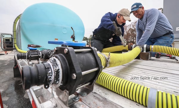 Mike Jett (left) and Bobby Garza (right) prepare brine trucks Friday morning at a Georgia Department of Transportation facility in Forest Park. JOHN SPINK / JSPINK@AJC.COM