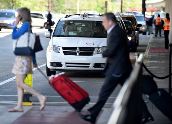 April 22, 2015 Atlanta: These arriving passengers were walking to an airport shuttle at Hartsfield Jackson International Airport, but some passengers are bypassing traditional transportation such as taxis and shuttles, instead opting for the growing popularity of social media based ride services such as Uber. BRANT SANDERLIN/BSANDERLIN@AJC.COM