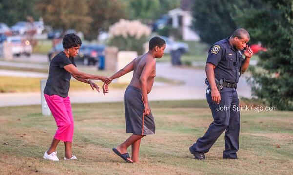 Officers escort residents in the Wesley Lakes neighborhood back into their homes after a SWAT standoff forced them to evacuate late Tuesday night.