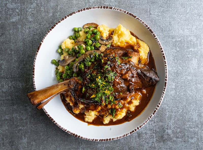 Osso buco lamb shank with creamy polenta, wild mushrooms and sprig pea compote is among entrees at La Panarda. / Courtesy of Josh Swinney