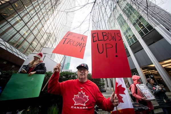 A demonstrator holds up signs during a protest outside of the U.S embassy in Vancouver, British Columbia, Tuesday, March 4, 2025. (Ethan Cairns/The Canadian Press via AP)