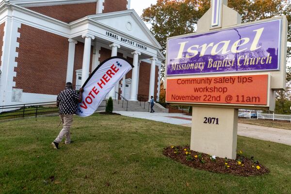 Assistant Poll Manager Jasper Perry situates the signage outside Israel Baptist Church on election day, Tuesday, Nov. 8, 2022.  (Steve Schaefer/steve.schaefer@ajc.com)