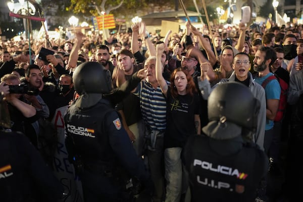 Demonstrators confront riot police during a protest organized by social and civic groups, denouncing the handling of recent flooding under the slogan "Mazón, Resign," aimed at the president of the regional government Carlos Mazon, in Valencia, Spain, Saturday, Nov. 9, 2024. (AP Photo/Emilio Morenatti)