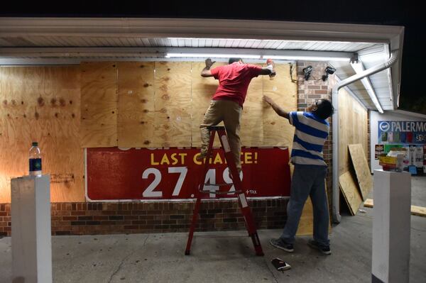 In Brunswick Thursday night, Jayesh Patel (left), owner, and Mahesh Patel board up their gas station ahead of Hurricane Matthew. HYOSUB SHIN / HSHIN@AJC.COM