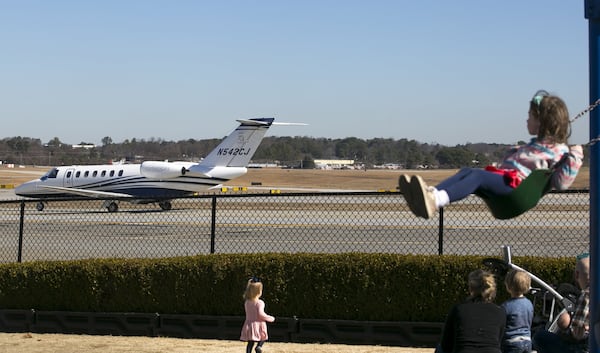 Kids watch from a playground as a jet moves along the tarmac at DeKalb-Peachtree Airport. (Casey Sykes for The Atlanta Journal-Constitution)