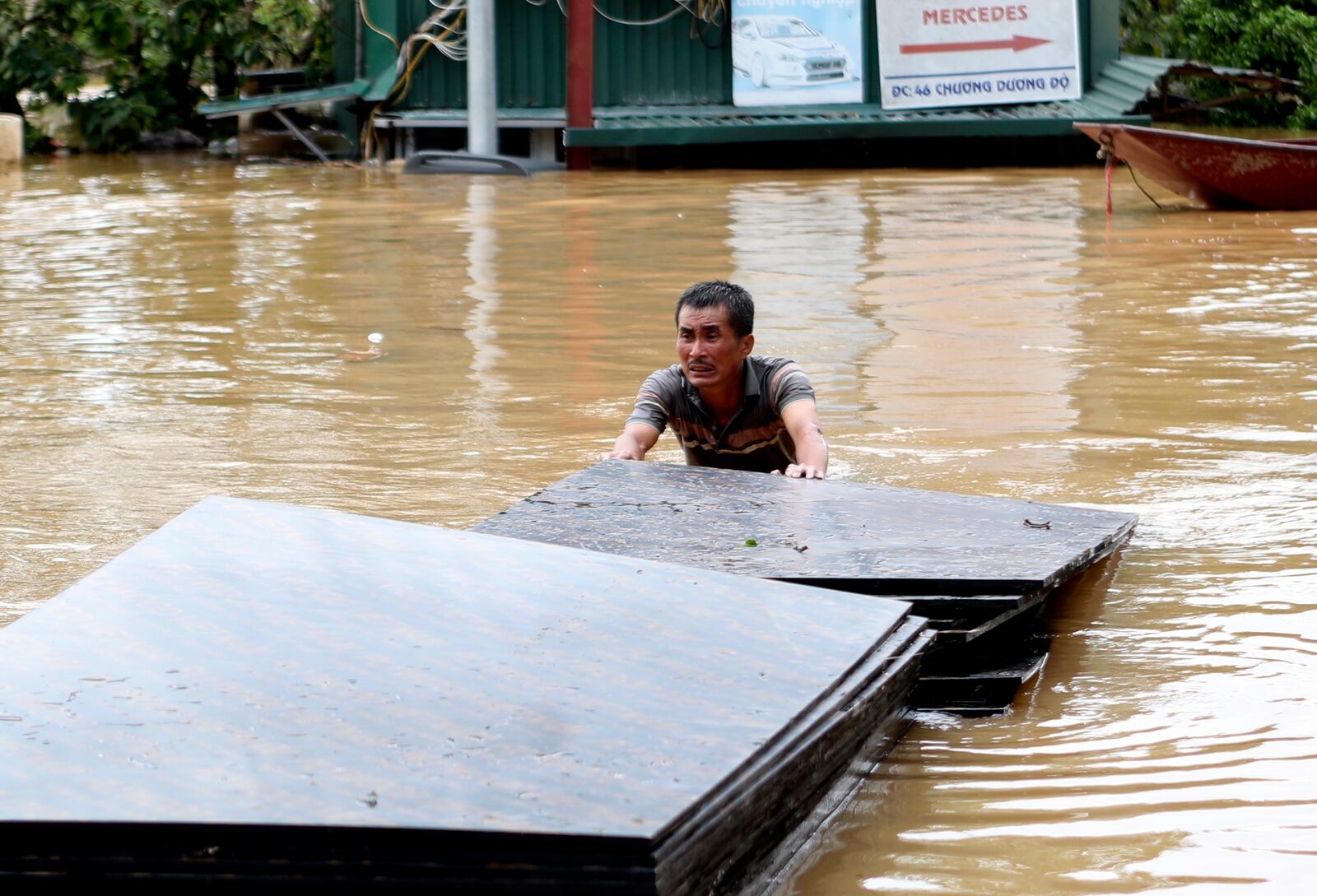 A man pushes a stack of plyboards in flood following Typhoon Yagi in Hanoi, Vietnam on Tuesday, Sept. 10, 2024. (AP Photo/Huy Han)