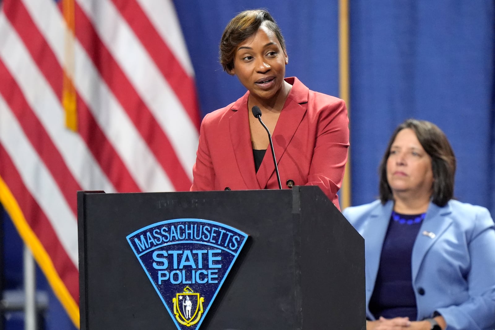 Massachusetts Attorney General Andrea Campbell, top, makes remarks during the swearing in of the 90th Recruit Training Group of the Massachusetts State Police, Wednesday, Oct. 9, 2024, at the DCU Center, in Worcester, Mass., as Mass. Lt. Gov. Kim Driscoll, right, looks on. (AP Photo/Steven Senne)