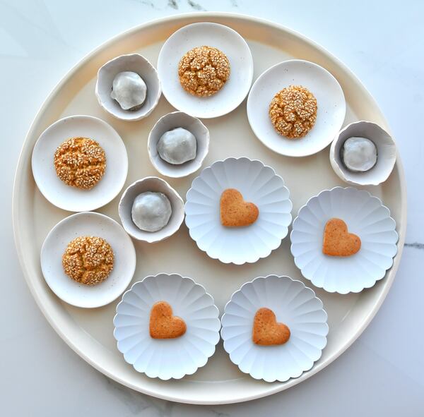 Deklah Polansky’s gluten-free tea cookies include Masala Chai Tea Cookies (heart-shaped), Brown Butter-Black Sesame Cookies (which look like pearls in a shell) and Tahini, Honey and Orange Cookies (brown cookies with sesame seeds on top). (Styling by Deklah Polansky / Chris Hunt for the AJC)