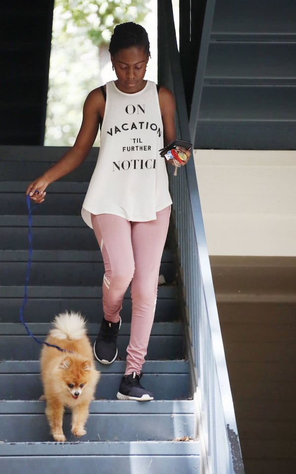 Jessica Melford takes her dog, Landon, for a walk outside her apartment. As a former ward of the state, Melford benefited from a program that provides financial and other support for former foster children beyond the age of 18. She just graduated from Georgia State and starts grad school Monday. BOB ANDRES / ROBERT.ANDRES@AJC.COM