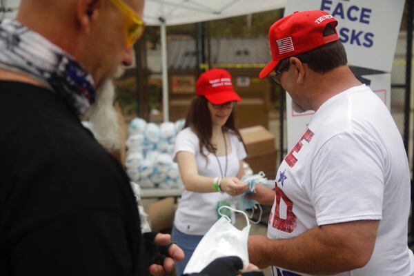 Masks to protect against COVID-19 are handed to supporters as they enter safety barricade for President Donald Trump's campaign rally on Saturday, June 20, 2020 in Tulsa, Oka.  (Mike Simons/Tulsa World via AP)