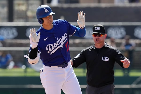 Los Angeles Dodgers designated hitter Shohei Ohtani, left, of Japan, pauses at second base with a double against the Texas Rangers as umpire Mike Muchlinski, right, calls for time during the first inning of a spring training baseball game Thursday, March 6, 2025, in Phoenix. (AP Photo/Ross D. Franklin)