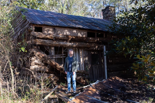 Trevor Beeman, executive director of Cobb Landmarks + Historical Society, poses in front of the circa 1840 Power-Jackson Cabin in Marietta on Monday, December 4, 2023. The organization hopes to restore and move the building. (Arvin Temkar / arvin.temkar@ajc.com)