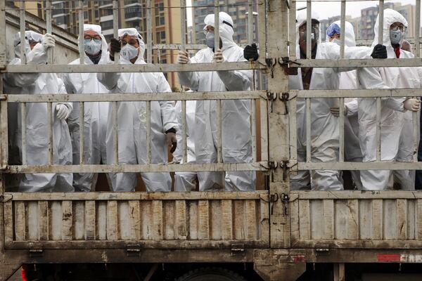 Workers in protective suits ride on a truck carrying medical supplies to a temporary hospital in Wuhan.