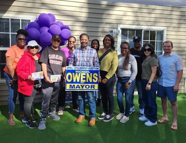 Michael Owens (center), a candidate for Mableton mayor, holds a sign advertising his campaign with a group of people at a campaign event. Provided by Michael Owens