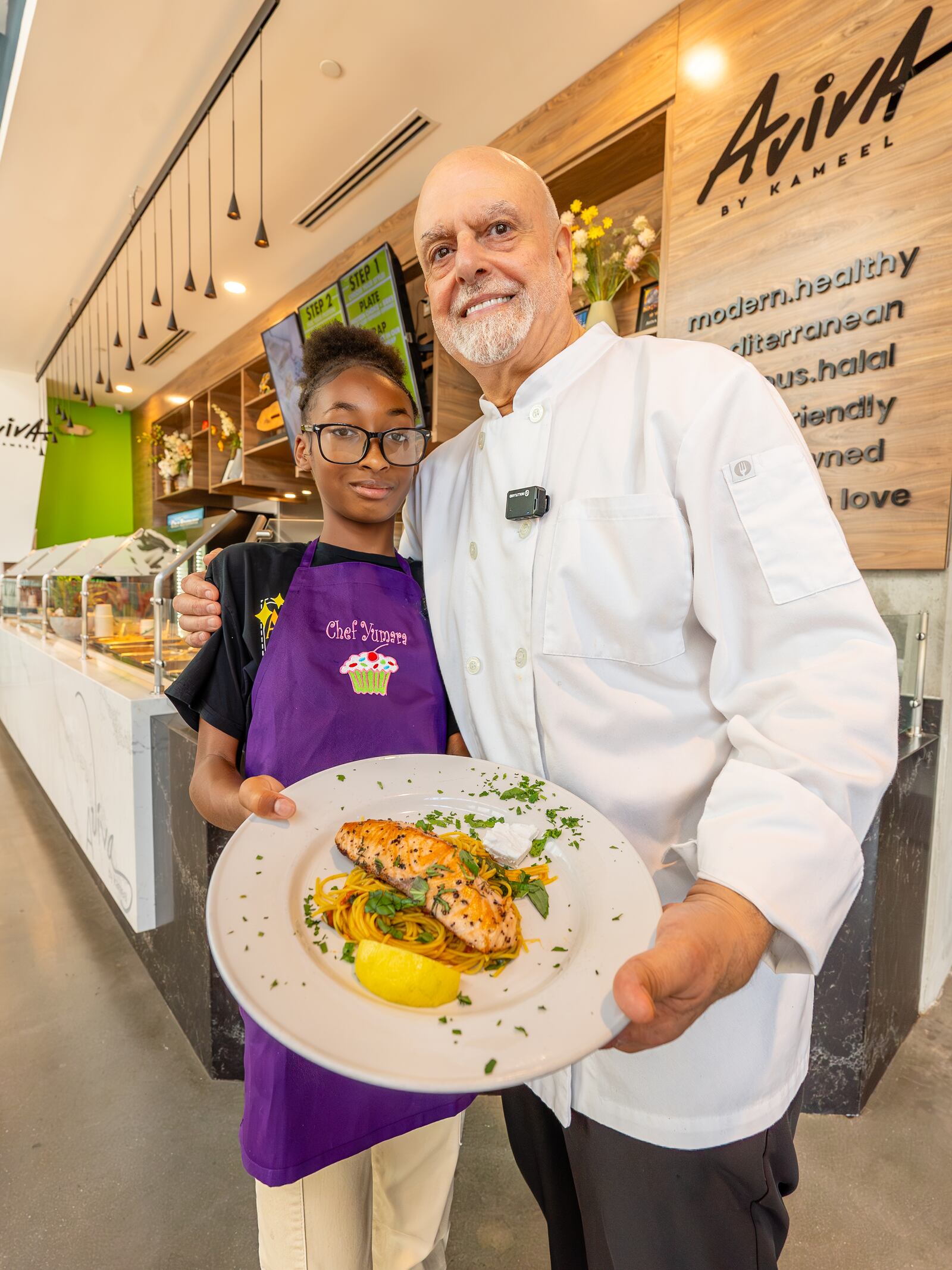 Chef Kameel Srouji and chef Yumara Nash cook salmon and pasta together in the Aviva by Kameel kitchen. Nash, 12, has built a following on social media for her cooking videos. Courtesy of J. Alburi/the Imprints