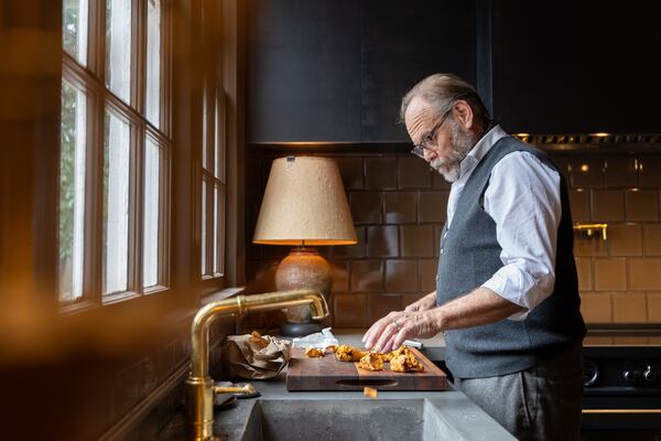 Alton Brown, 62, cuts chanterelle mushrooms to add to scrambled eggs at his newly renovated kitchen in Atlanta that includes a beloved induction range. (Arvin Temkar / AJC)