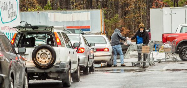 Volunteers at the New City Church food pantry in Peachtree City distribute dry goods, fresh vegetables and frozen meats to waiting cars outside the food pantry. (Jenni Girtman for The Atlanta Journal-Constitution)