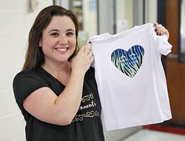 Nikki Rajahn shows the winning T-shirt design (“Kindness Starts With a Smile”) from a schoolwide competition at North Fayette Elementary School. BOB ANDRES / ROBERT.ANDRES@AJC.COM