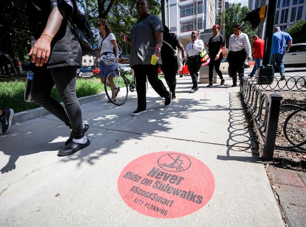 People walk on a sidewalk on West Peachtree Street near where William Alexander was hit and killed by a bus while riding on a scooter. At a protest held Wednesday, July 24, 2019, organizers joined together as a “human protected sidewalk, bike and scooter lane” demanding the city prioritize protected lanes for alternative transportation such as bikes and e-scooters. BRANDEN CAMP/SPECIAL