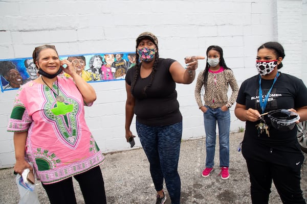  Artist Ashley Dopson (center) talks with Deborah Scott (left), executive director of Georgia Stand Up, about the "Heroine" mural Dopson is painting in Atlanta's West End. STEVE SCHAEFER / FOR THE AJC 