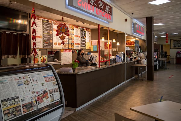 Guijie Zhang, owner of China Kitchen, a small food booth located inside the Atlanta Chinatown Shopping Mall food court, waits for a customer during a lull in the late afternoon at her booth in Chamblee, Friday, July 31, 2020. Zhang has installed a clear barrier between herself and her customers near the register for protection against the transmission of germs. (ALYSSA POINTER / ALYSSA.POINTER@AJC.COM)