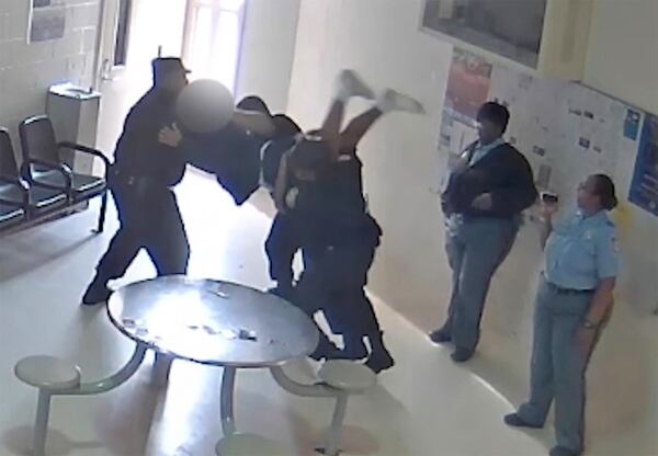 In an image taken from surveillance video, three corrections officers prepare to slam a youth to the floor. The three officers lost their jobs for using excessive force, but they faced no criminal charges.