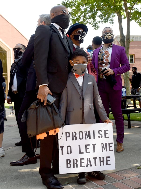 Young Roman Thomas, 7, stands with his father Ro Thomas at the George Floyd memorial held at the Martin Luther King Park. (Photo: Ryon Horne/AJC)