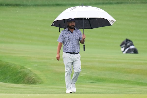 J.J. Spaun holds an umbrella while walking away from the 11th green during the final round of The Players Championship golf tournament Sunday, March 16, 2025, in Ponte Vedra Beach, Fla. (AP Photo/Chris O'Meara)