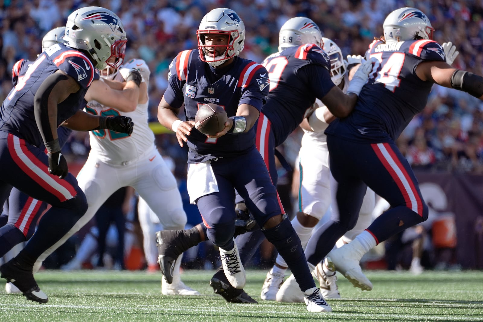 New England Patriots quarterback Jacoby Brissett, center, sets to hand off the ball against the Miami Dolphins during the second half of an NFL football game, Sunday, Oct. 6, 2024, in Foxborough, Mass. (AP Photo/Michael Dwyer)