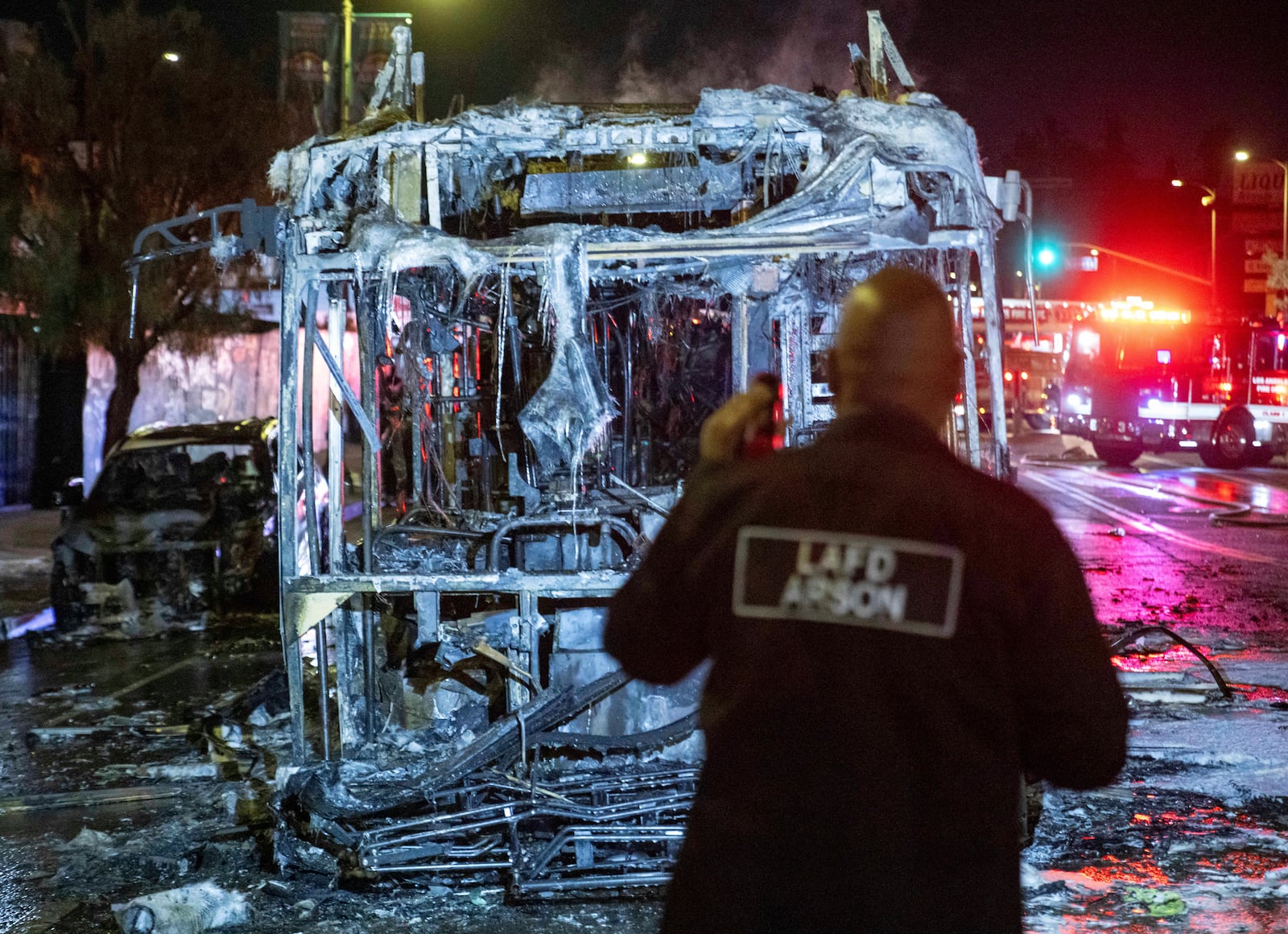 An LAFD arson investigator inspects a bus that was set on fire at Sunset and Echo Park after people gathered on the streets after the Los Angeles Dodgers defeated the New York Yankees to win the baseball World Series early Thursday, Oct. 31, 2024, in Los Angeles. (AP Photo/Ethan Swope)